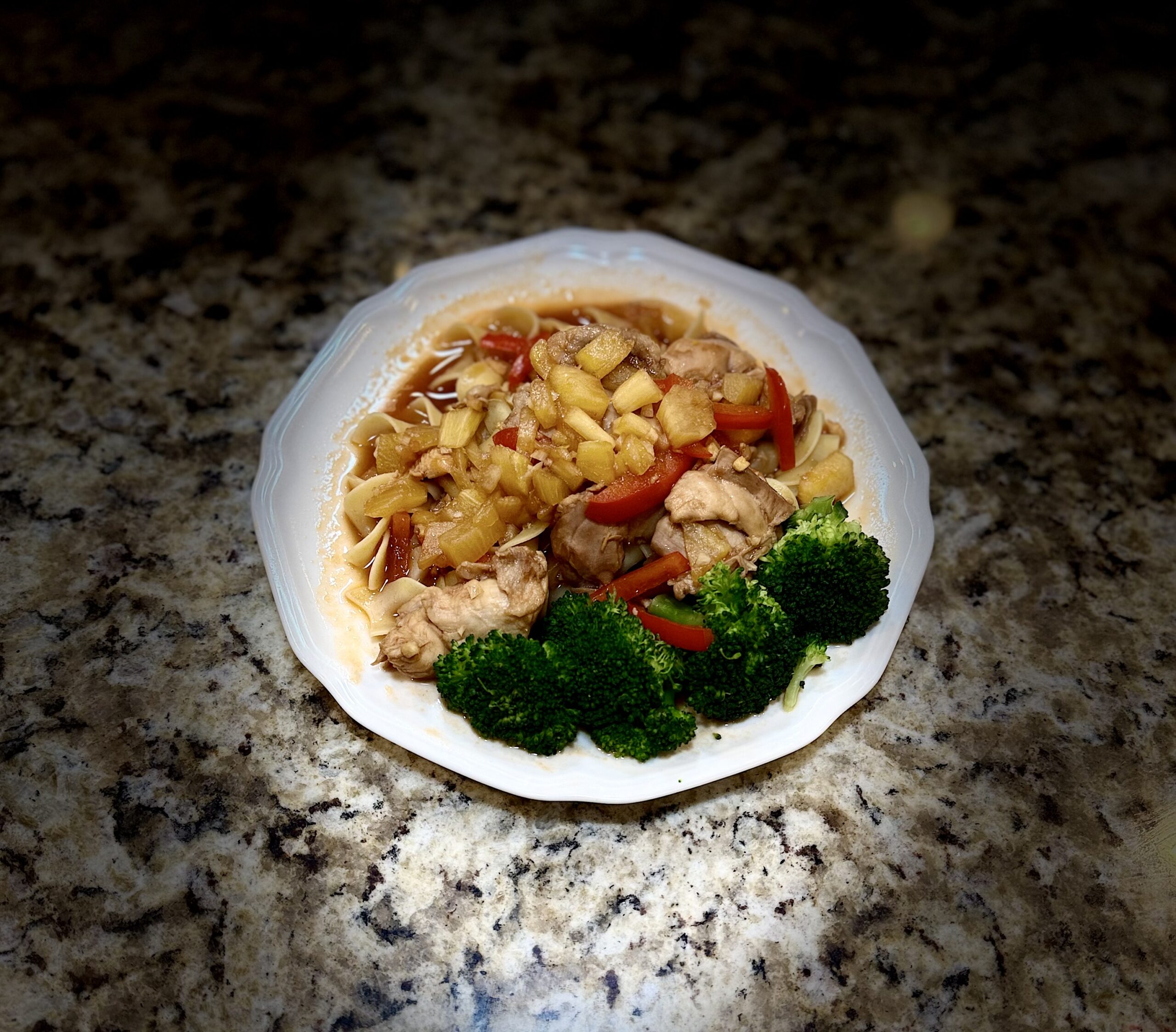 Huli skillet chicken thighs glazed in pineapple-soy sauce with red bell pepper over noodles