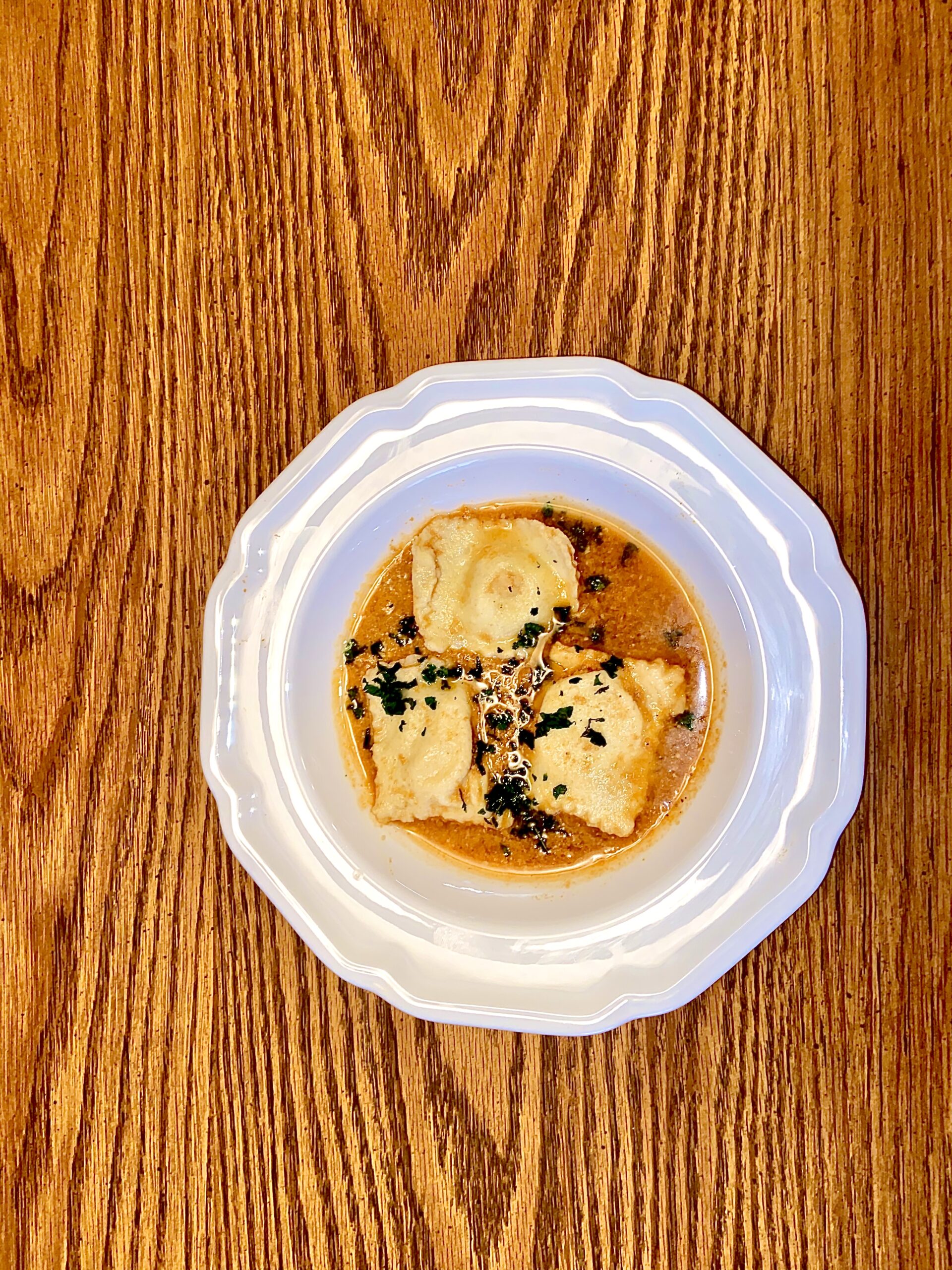 Maryland crab ravioli in a tomato crab bisque, garnished with fresh herbs